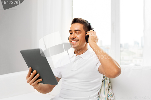 Image of smiling man with tablet pc and headphones at home