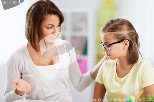 Image of upset mother talking to daughter doing homework