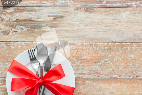 Image of cutlery tied with red ribbon on set of plates