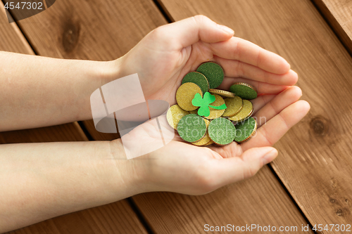 Image of hands with golden coins and shamrock leaf