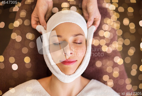 Image of woman having face massage with towel at spa