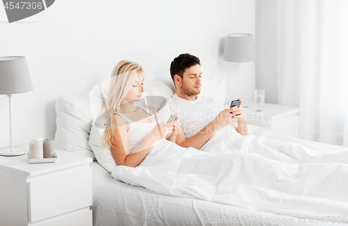 Image of couple with smartphones in bed