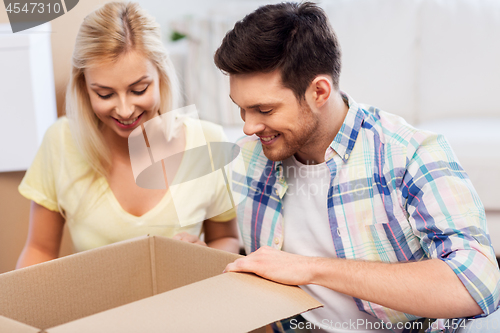 Image of happy couple looking inside box or parcel at home