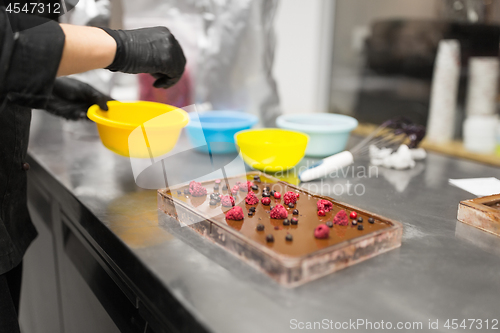 Image of confectioner makes chocolate dessert at sweet-shop