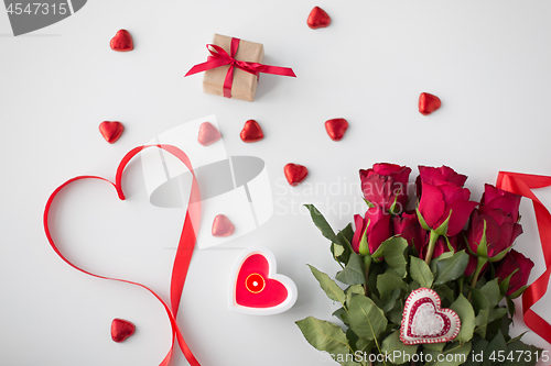 Image of close up of red roses, gift, candies and candle