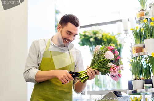 Image of smiling florist man making bunch at flower shop