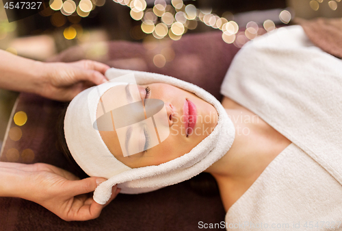 Image of woman having face massage with towel at spa