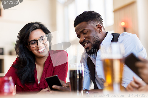 Image of happy man and woman with smartphones at bar
