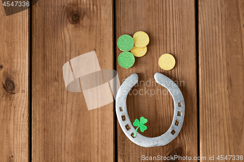 Image of horseshoe with shamrock on wooden background