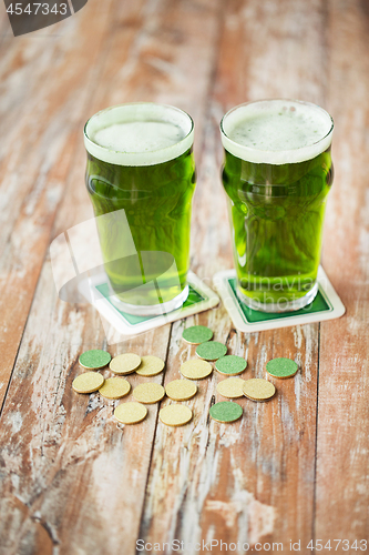 Image of glasses of green beer and gold coins on table