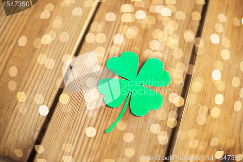 Image of green paper four-leaf clover on wooden background