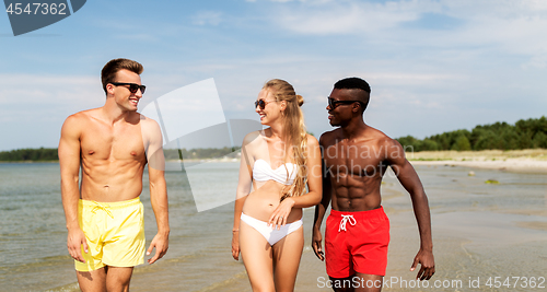 Image of happy friends walking along summer beach