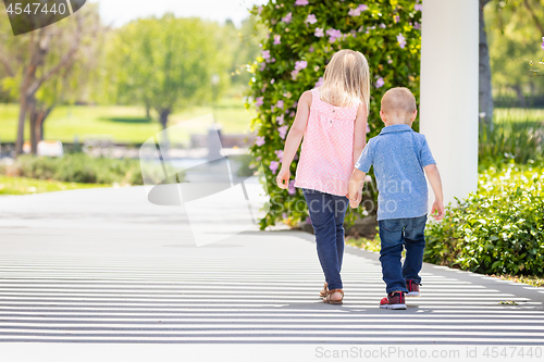 Image of Young Sister and Brother Holding Hands And Walking At The Park