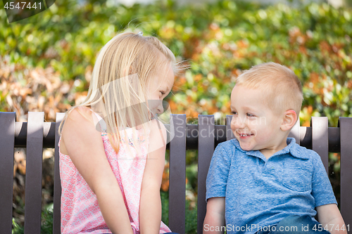 Image of Young Sister and Brother Having Fun On The Bench At The Park