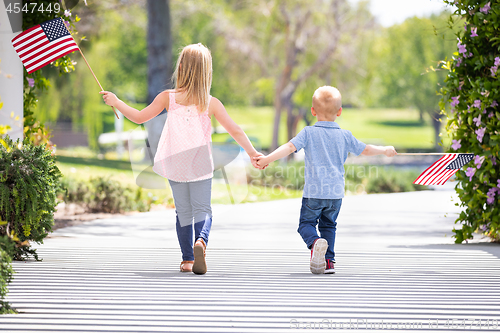 Image of Young Sister and Brother Holding Hands and Waving American Flags