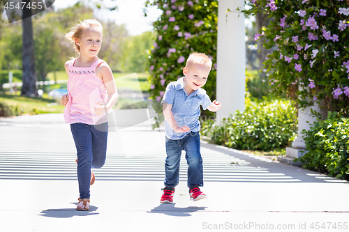 Image of Young Sister and Brother Having Fun Running At The Park