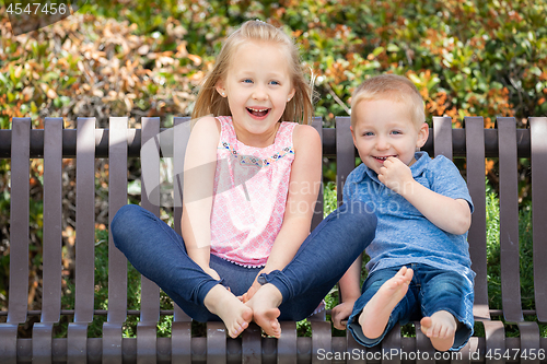 Image of Young Sister and Brother Having Fun On The Bench At The Park