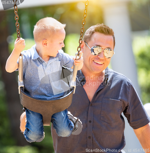 Image of Happy Young Boy Having Fun On The Swings With His Father At The 