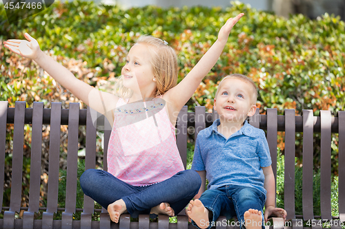 Image of Young Sister and Brother Having Fun On The Bench At The Park