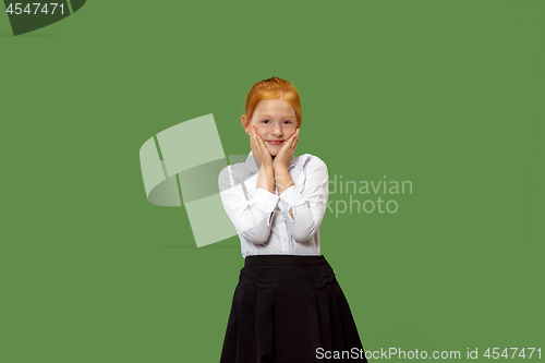 Image of The happy teen girl standing and smiling against green background.