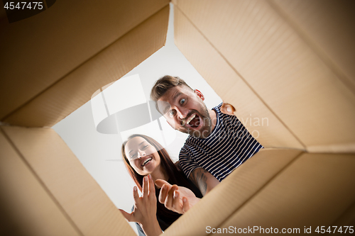 Image of The couple unpacking and opening carton box and looking inside