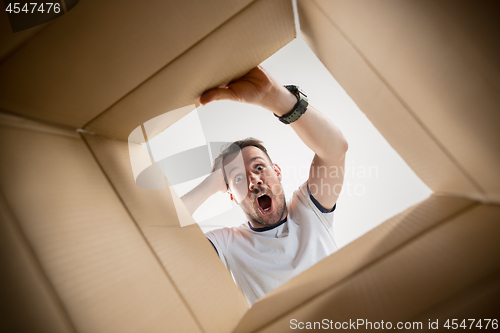 Image of Man unpacking and opening carton box and looking inside