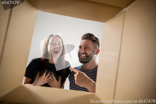 Image of The couple unpacking and opening carton box and looking inside