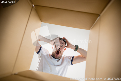 Image of Man unpacking and opening carton box and looking inside