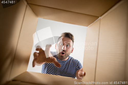 Image of Man unpacking and opening carton box and looking inside