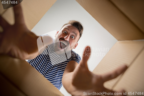 Image of Man unpacking and opening carton box and looking inside