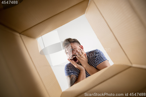 Image of Man unpacking and opening carton box and looking inside