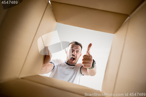 Image of Man unpacking and opening carton box and looking inside