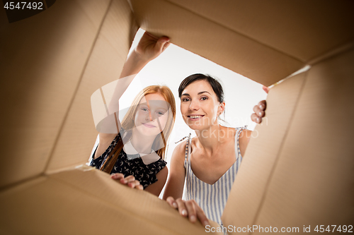 Image of mom and daughter unpacking and opening carton box and looking inside