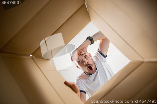 Image of Man unpacking and opening carton box and looking inside