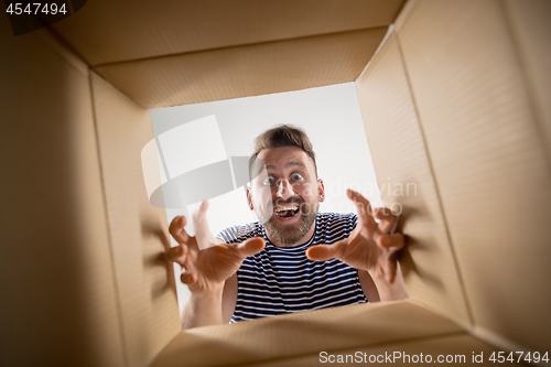 Image of Man unpacking and opening carton box and looking inside