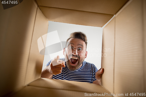 Image of Man unpacking and opening carton box and looking inside