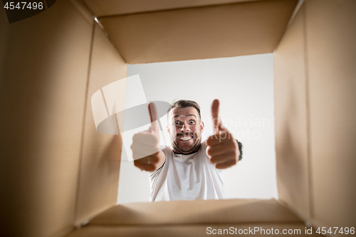 Image of Man unpacking and opening carton box and looking inside