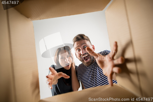 Image of The couple unpacking and opening carton box and looking inside