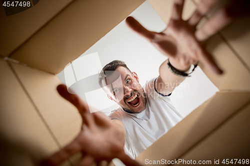 Image of Man unpacking and opening carton box and looking inside