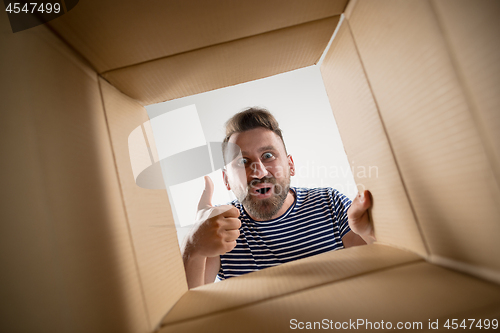 Image of Man unpacking and opening carton box and looking inside