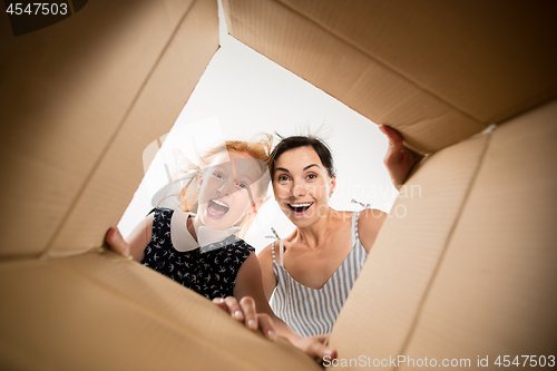 Image of mom and daughter unpacking and opening carton box and looking inside