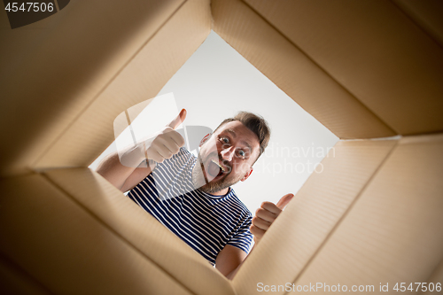 Image of Man unpacking and opening carton box and looking inside