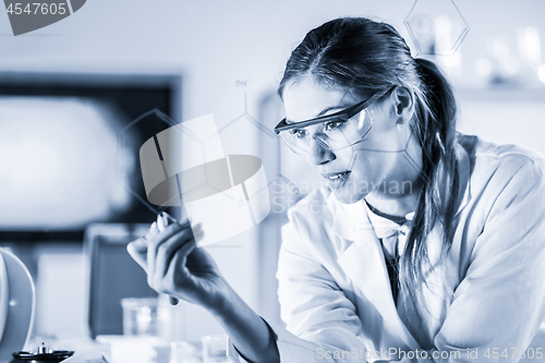 Image of Portrait of a confident female researcher in life science laboratory writing structural chemical formula on a glass board.