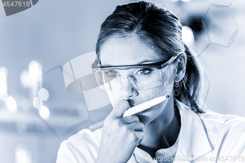 Image of Portrait of a confident female researcher in life science laboratory writing structural chemical formula on a glass board.