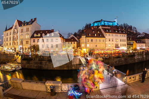 Image of View of lively river Ljubljanica bank in old city center decorated with Christmas lights at dusk. Old medieval Ljubljana cstle on the hill obove the city. Ljubljana, Slovenia, Europe