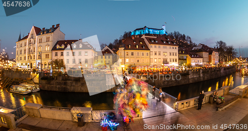 Image of View of lively river Ljubljanica bank in old city center decorated with Christmas lights at dusk. Old medieval Ljubljana cstle on the hill obove the city. Ljubljana, Slovenia, Europe