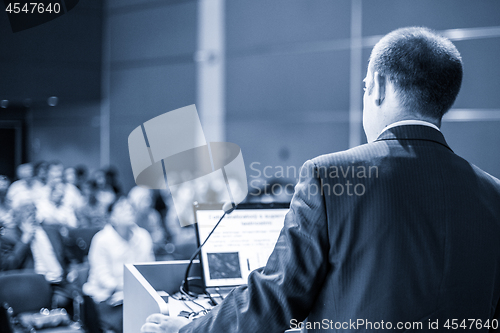 Image of Public speaker giving talk at business event.