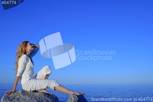 Image of Relaxed young woman enjoying sunset by the sea