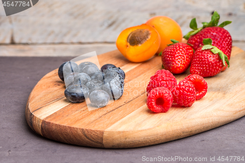 Image of Wooden board with fresh organic fruit and berries