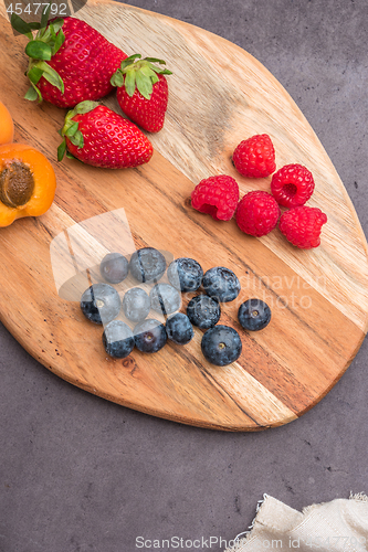 Image of Wooden board with fresh organic fruit and berries